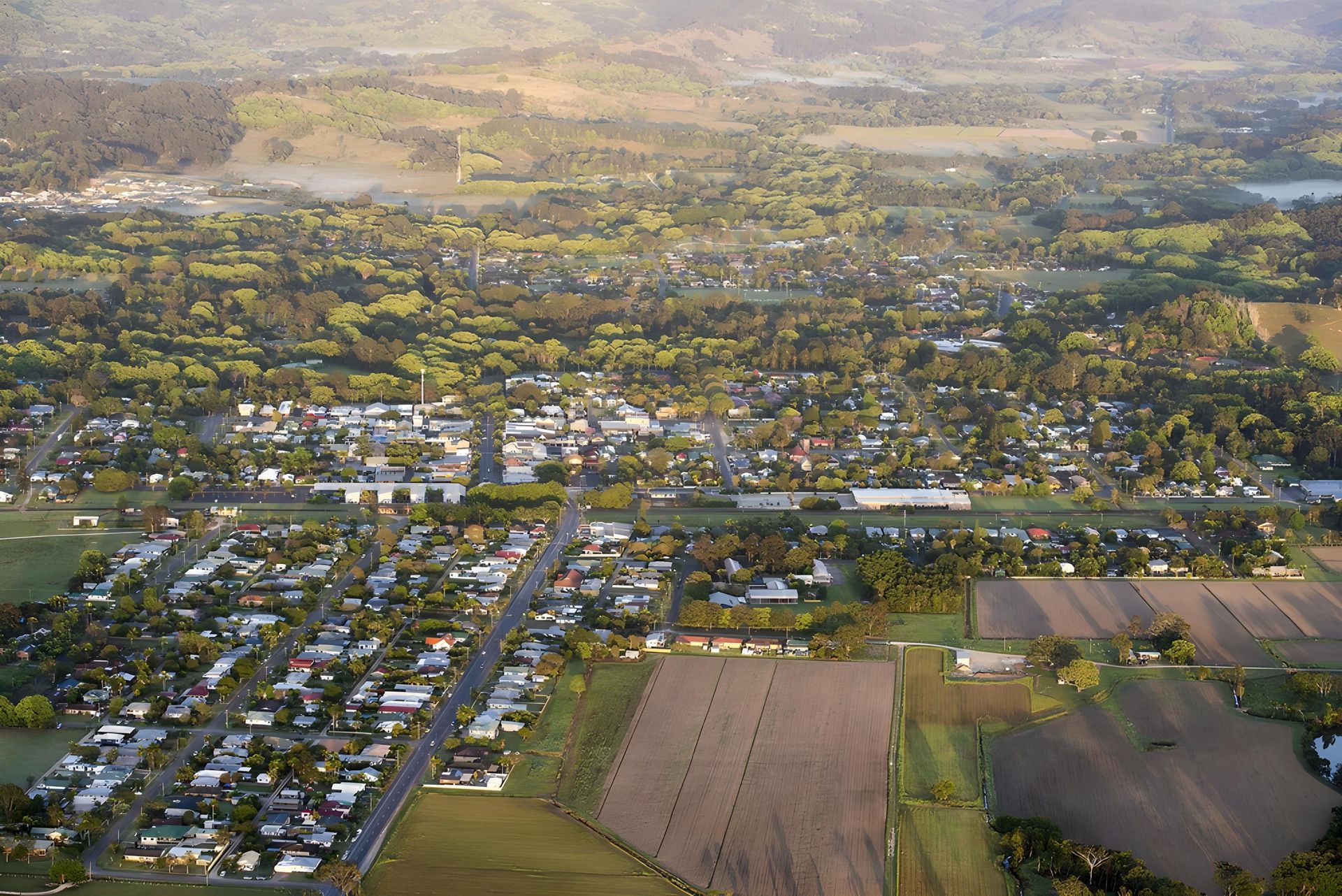 Aerial View of a Town With Buildings, Roads, and Fields, Surrounded by Trees — Hasti Skips in Mullumbimby, NSW