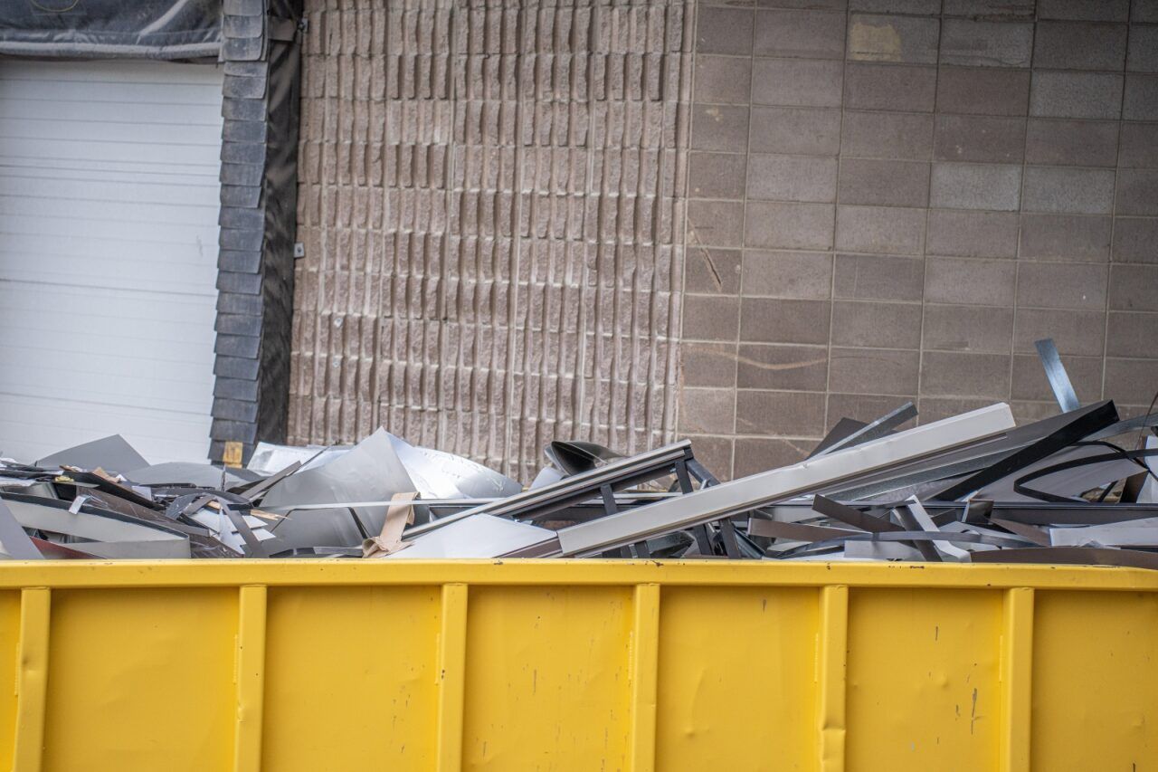 Yellow Dumpster Overflowing With Construction Debris Against a Textured Building Facade — Hasti Skips in Murwillumbah, NSW