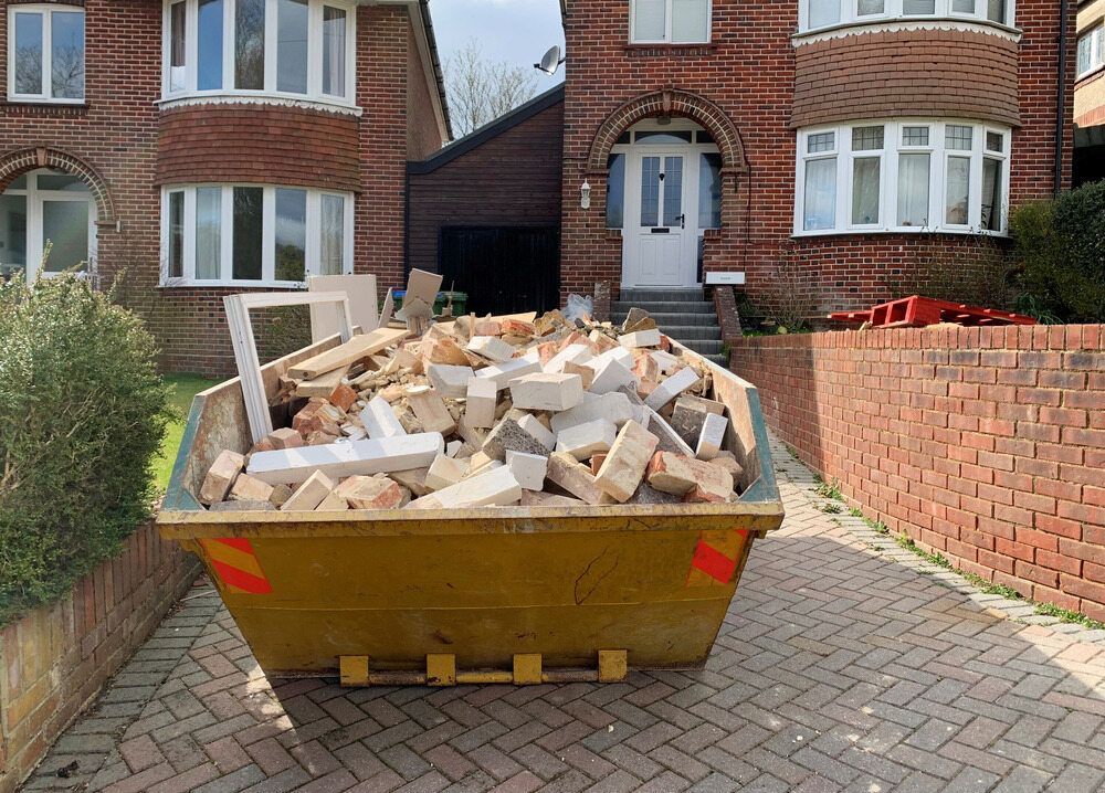 A Dumpster Filled With Construction Debris Sits on a Brick Driveway— Hasti Skips in Mullumbimby, NSW