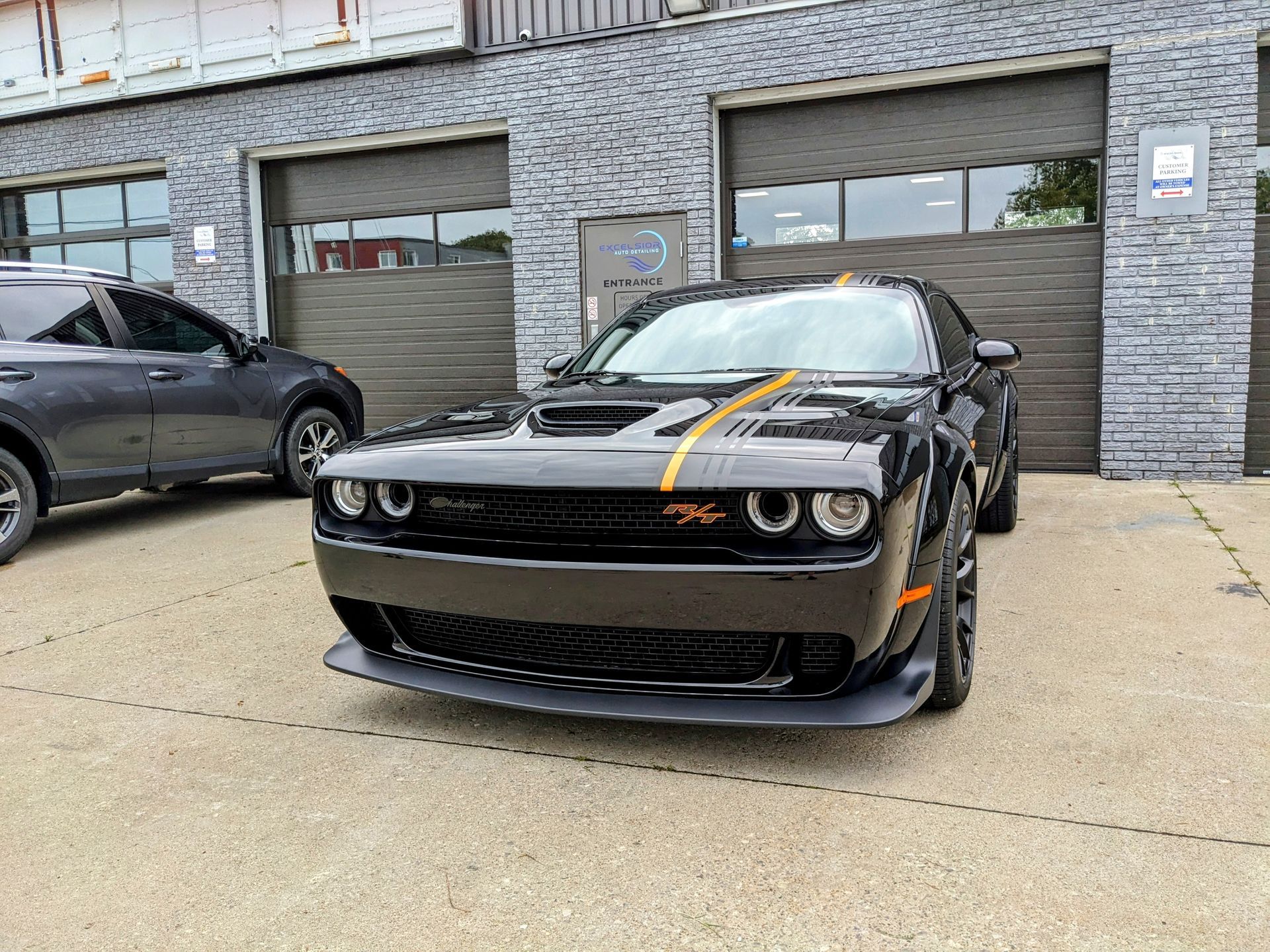 A black dodge challenger is parked in front of a garage.