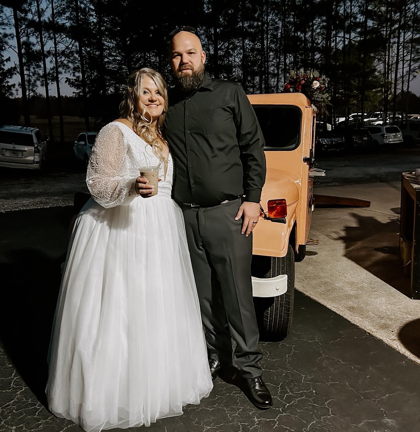 A bride and groom are posing for a picture in front of a jeep.