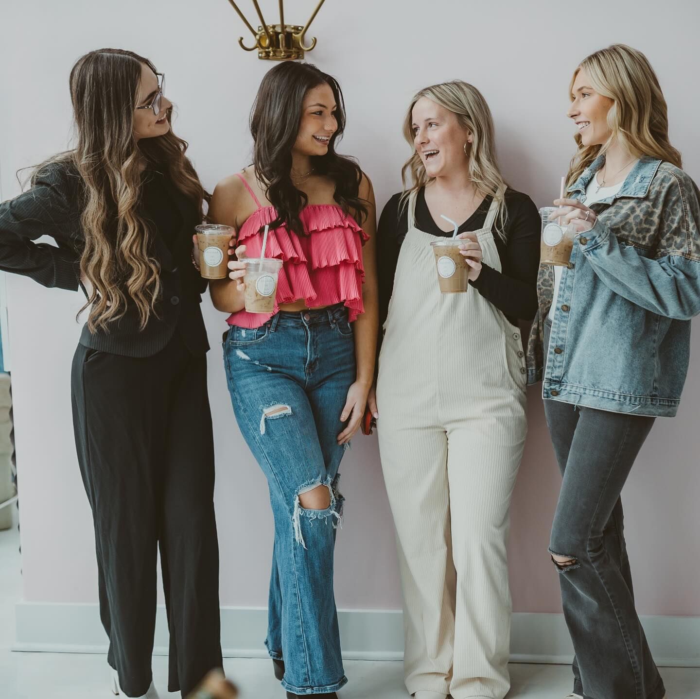 Four women standing next to each other holding cups of coffee