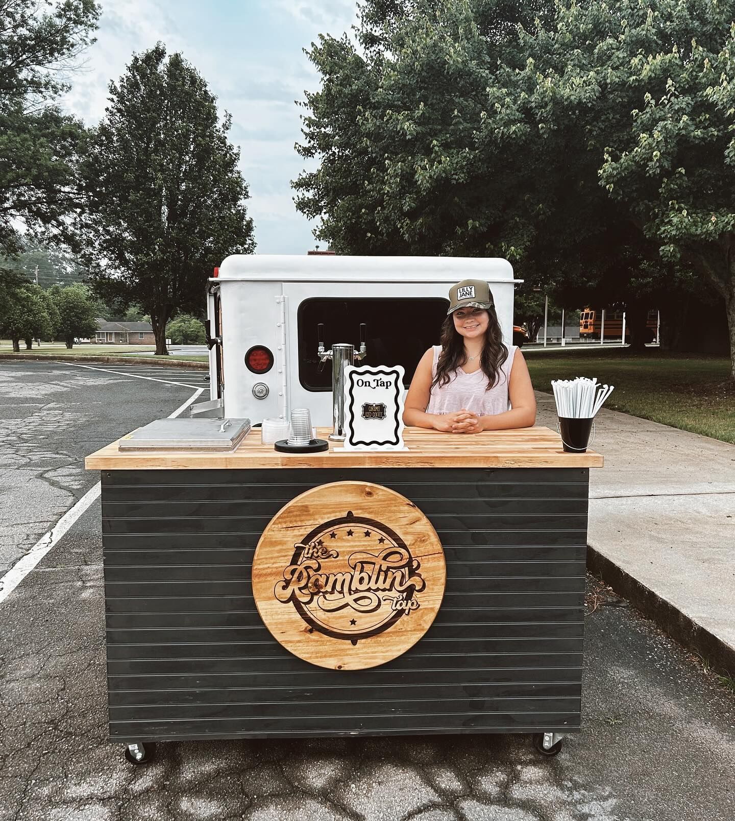 A woman is standing in front of a food truck.
