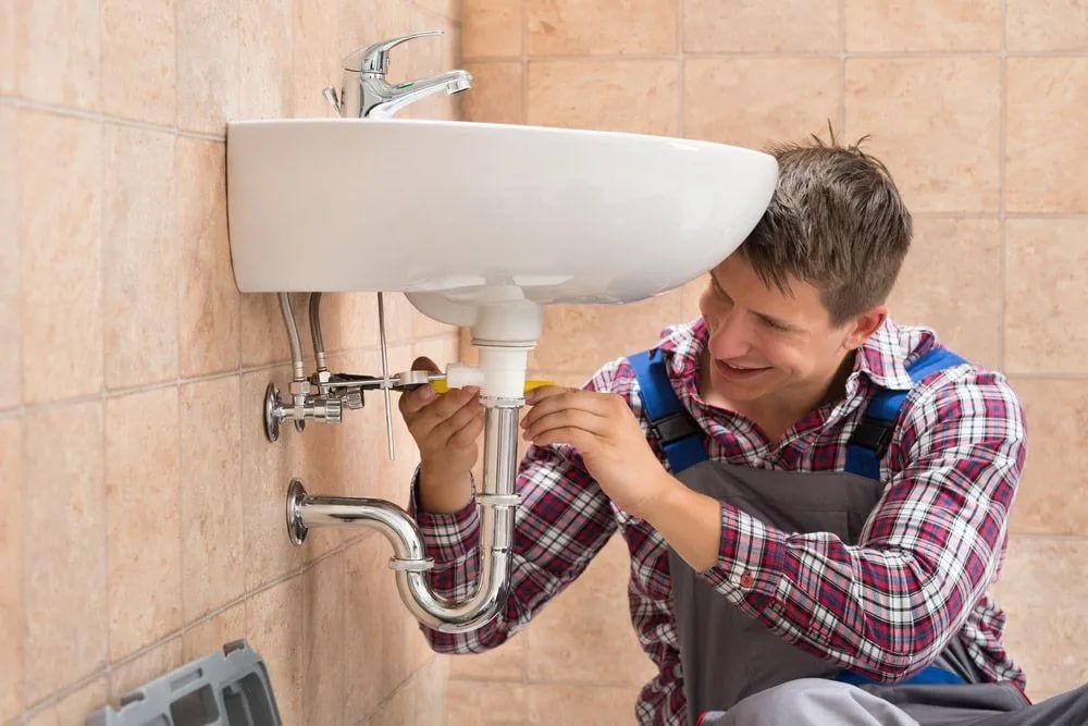 A Plumber is Fixing a Sink in a Bathroom — Foreshore Plumbers In Tuncurry, NSW