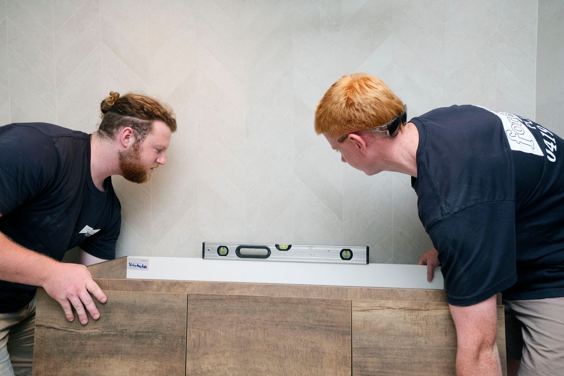 Two Men Are Measuring a Bathtub With a Level — Foreshore Plumbers In Tuncurry, NSW