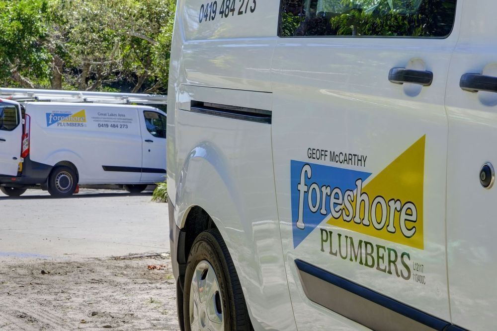 Two White Vans Are Parked Next to Each Other on the Side of the Road — Foreshore Plumbers in Tuncurry, NSW