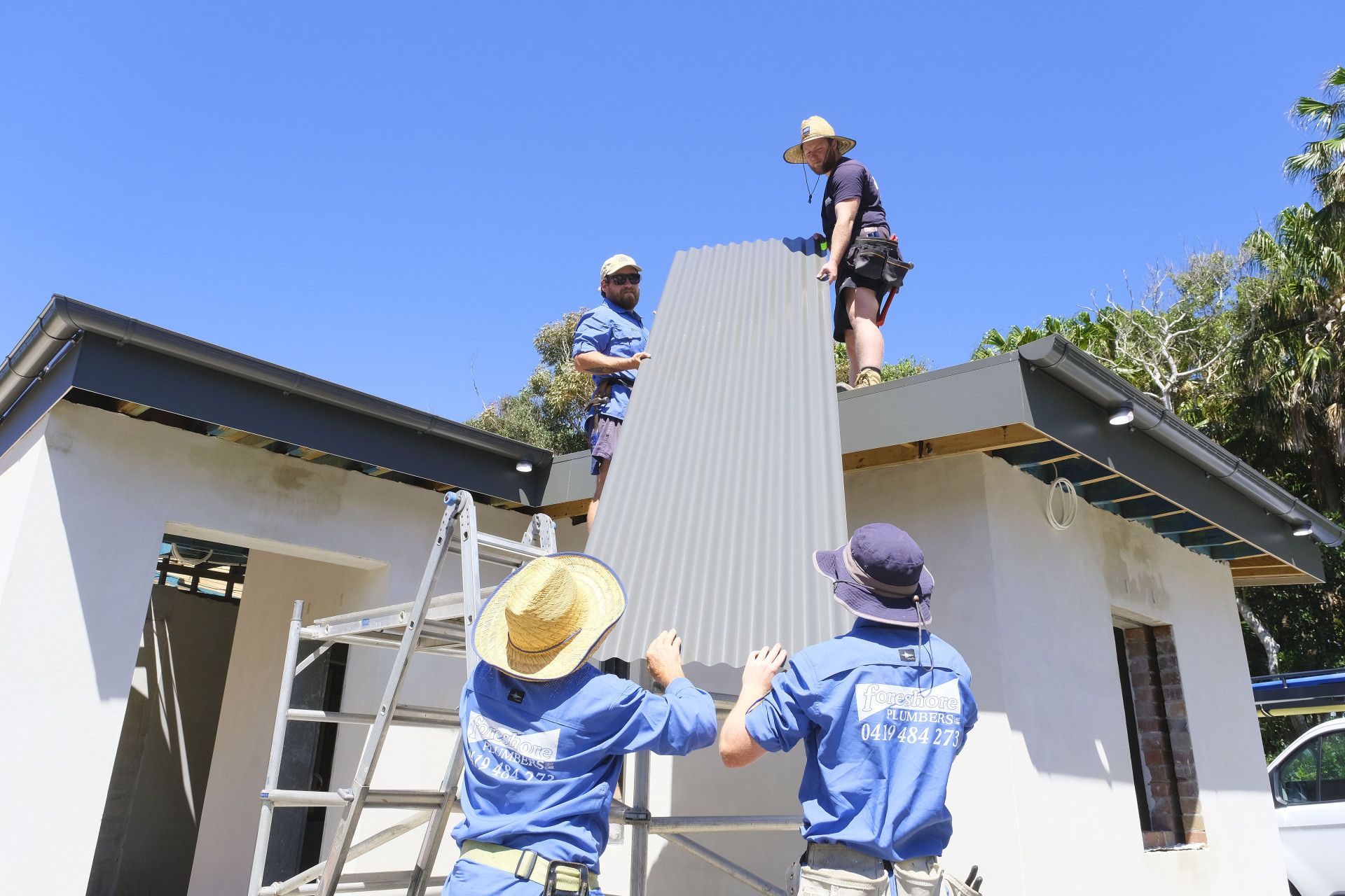 A Group of Men Are Working on the Roof of a House — Foreshore Plumbers in Tuncurry, NSW