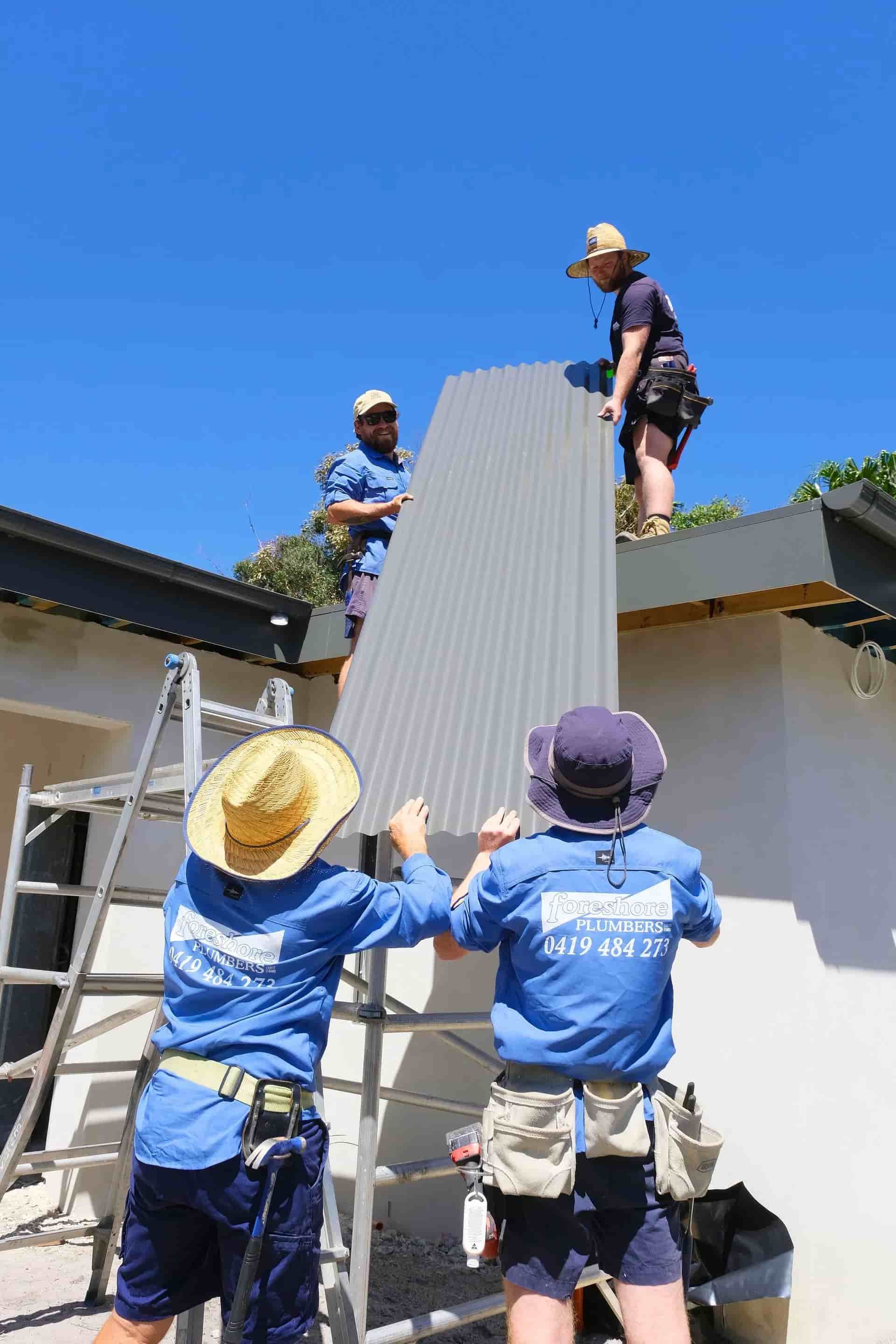 A Group of Construction Workers Are Working on a Roof — Foreshore Plumbers In Tuncurry, NSW