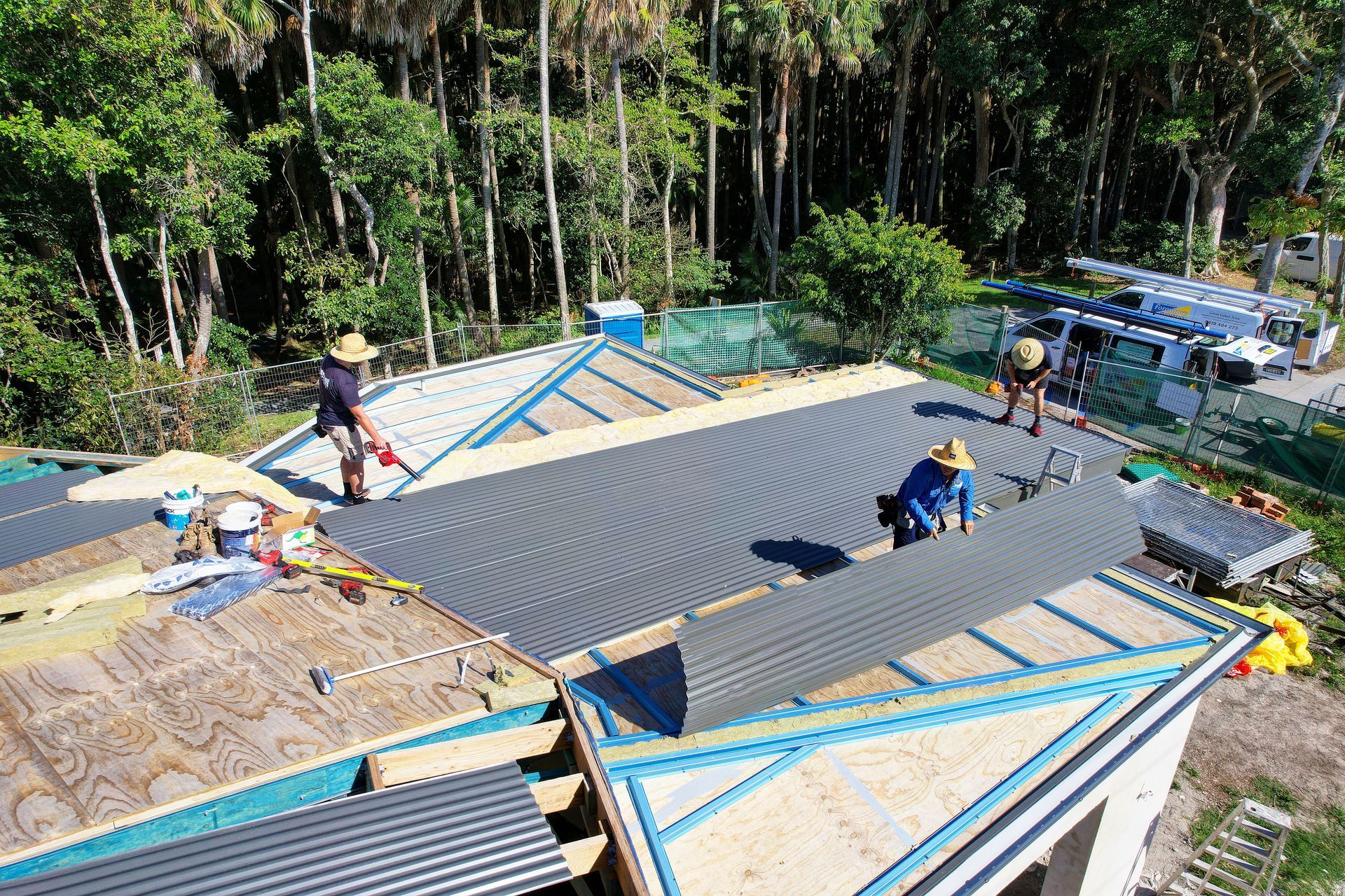 A Group of Construction Workers Are Working on the Roof of a House — Foreshore Plumbers in Tuncurry, NSW