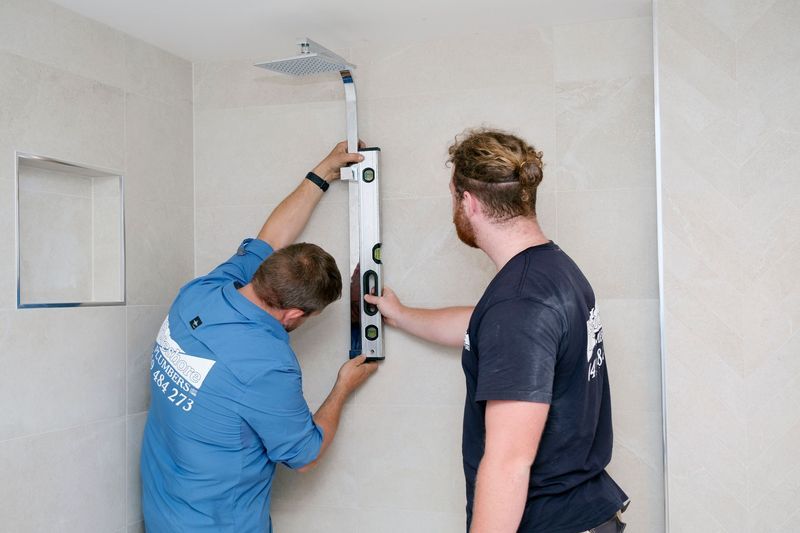 Two Men Are Measuring a Shower Head With a Level — Foreshore Plumbers in Tuncurry, NSW