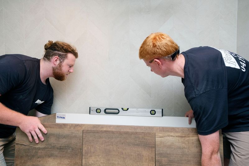 Two Men Are Using a Level to Check the Level of a Bathroom Vanity — Foreshore Plumbers in Tuncurry, NSW