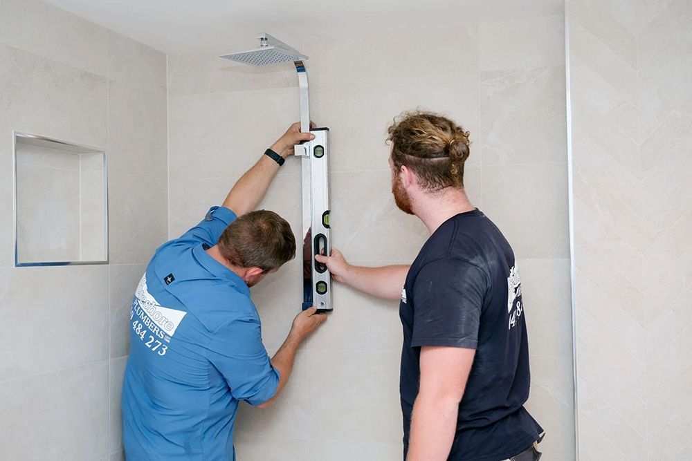 Two Men Are Measuring a Shower Head with a Level