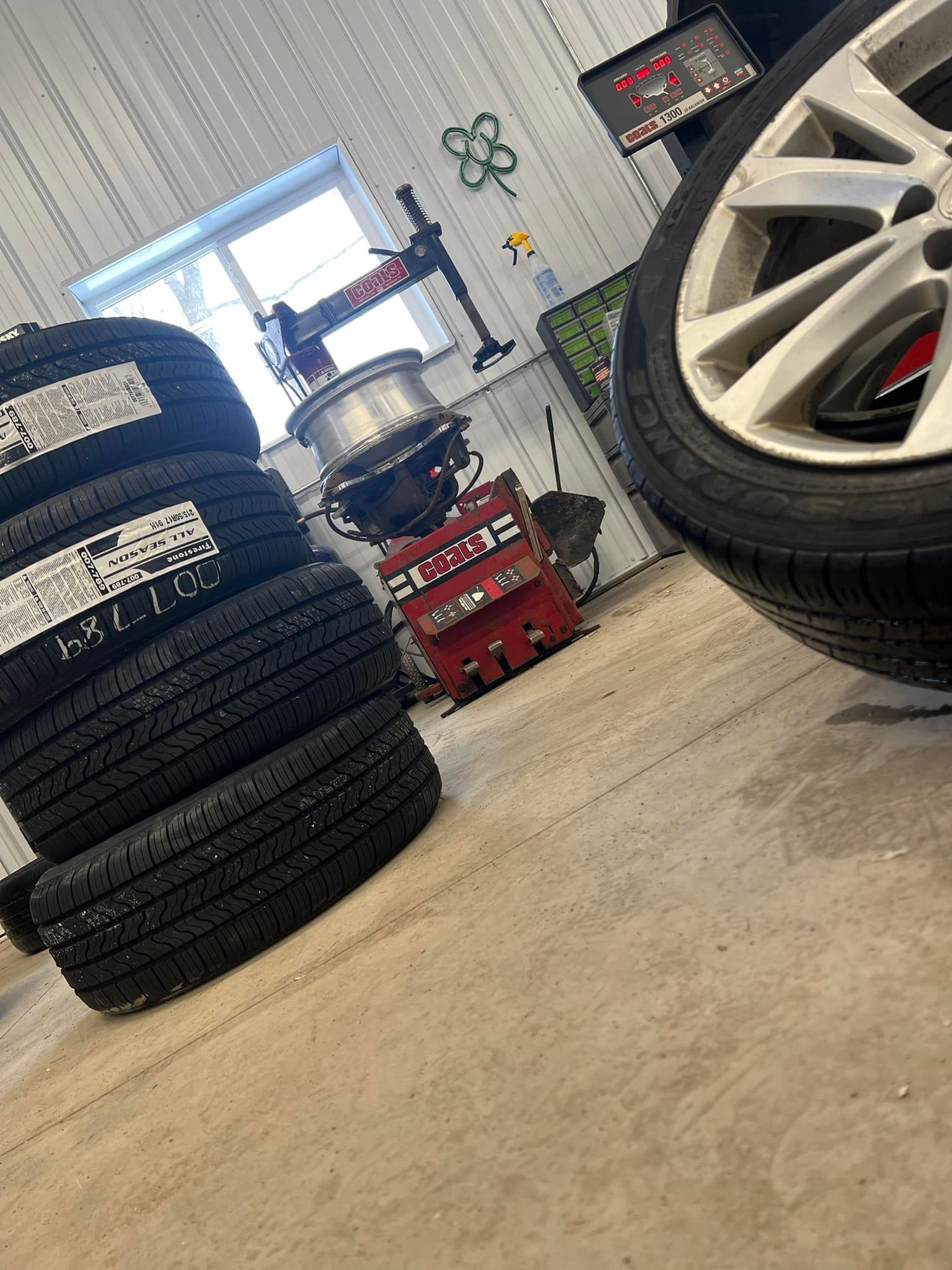 Family standing in front of a gray garage. Holding a sign with a phone number. | The Neighborhood Mechanic LLC
