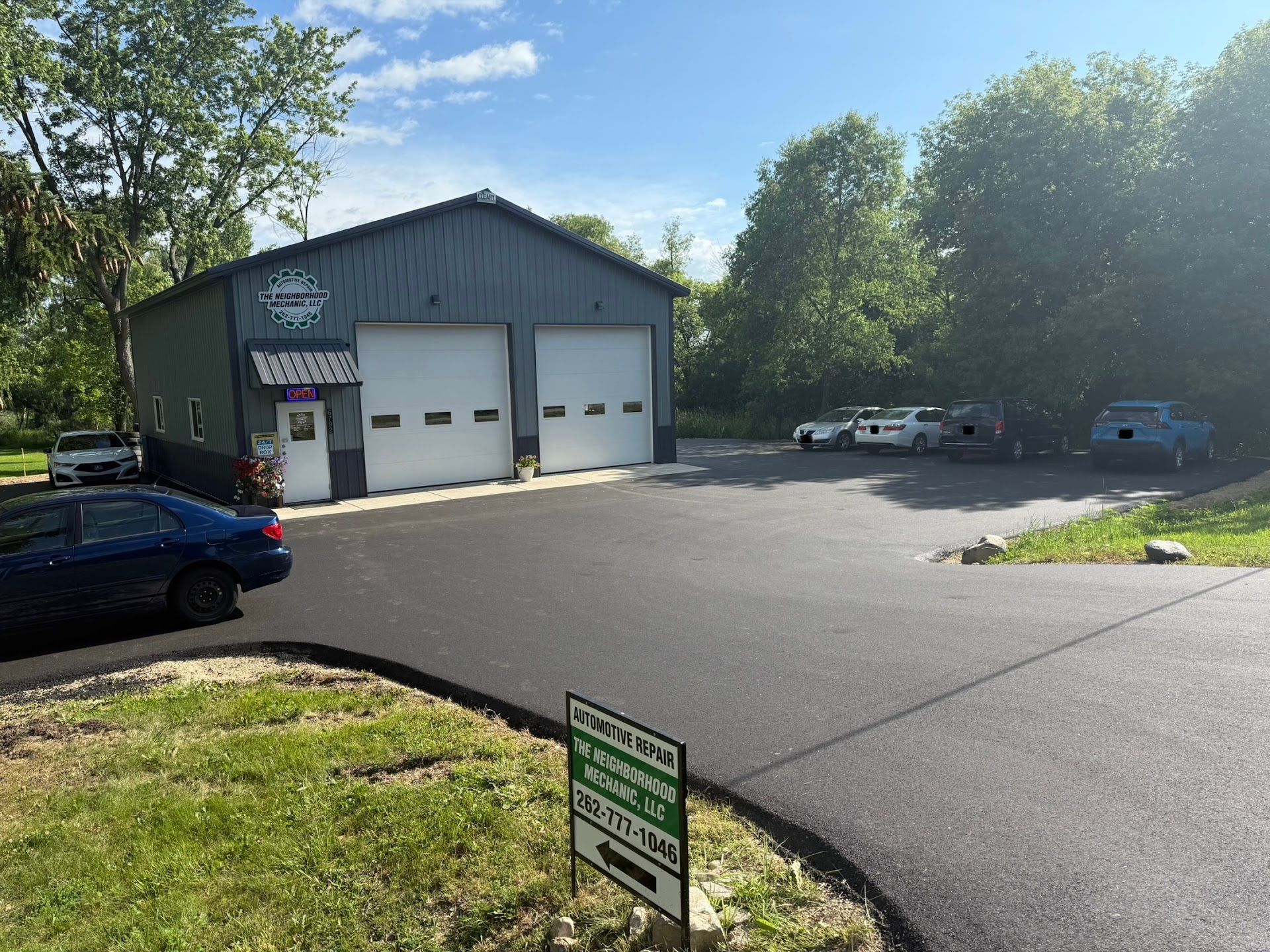 Gray and black garage with two overhead doors and a sign | The Neighborhood Mechanic LLC