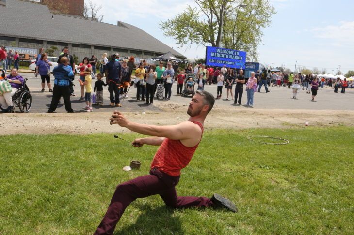 A man in a red tank top is kneeling on the grass in front of a crowd.