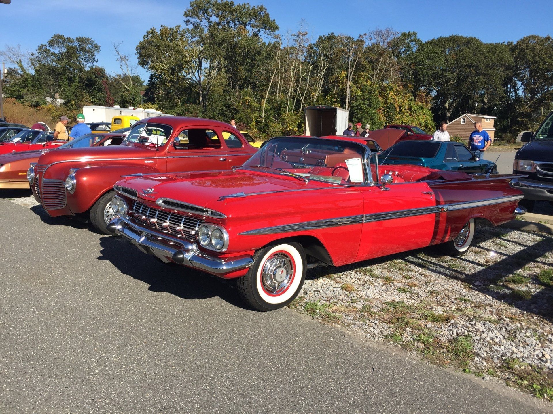 A row of red cars are parked on the side of the road.