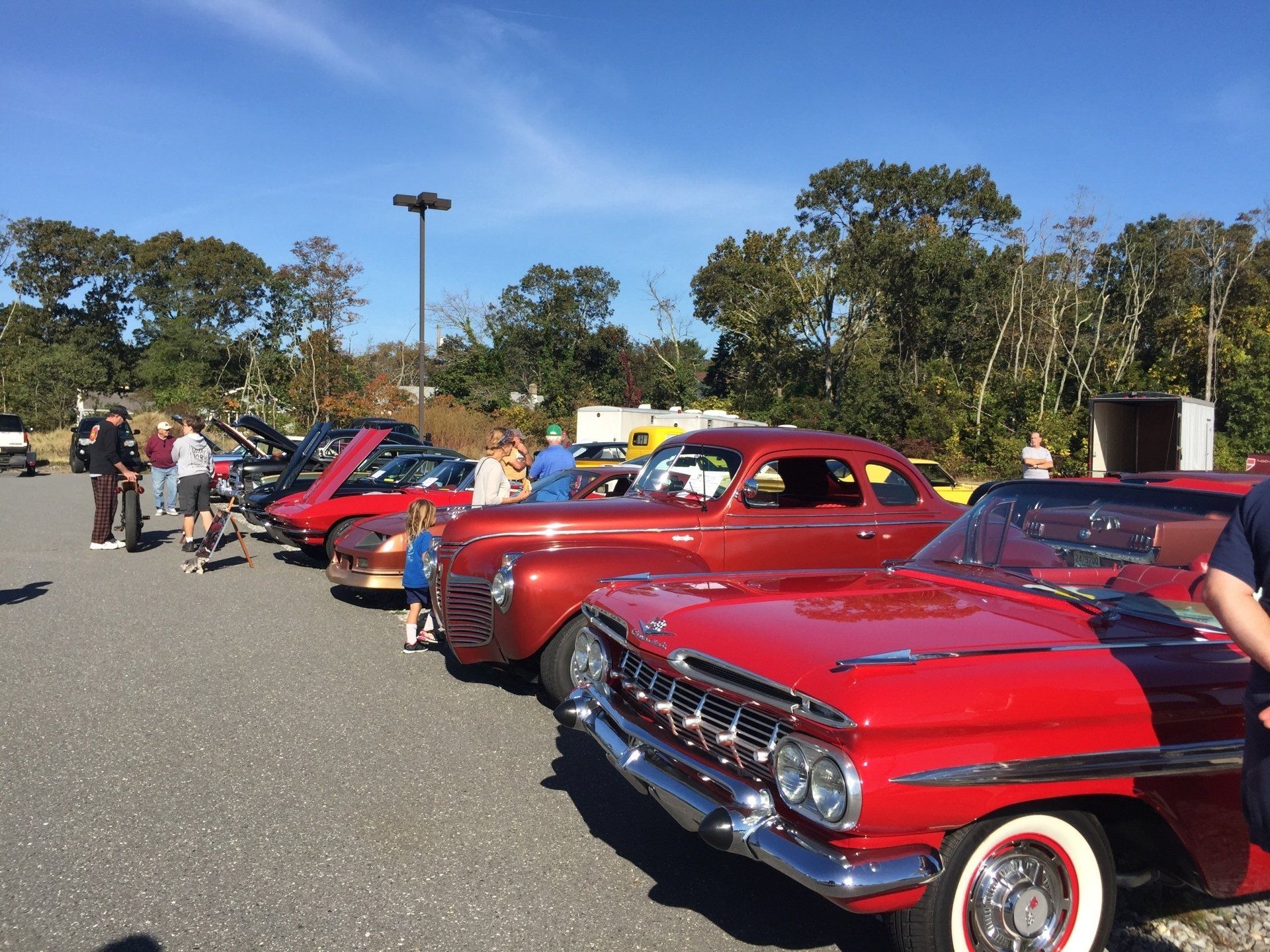 A row of red cars are parked in a parking lot.