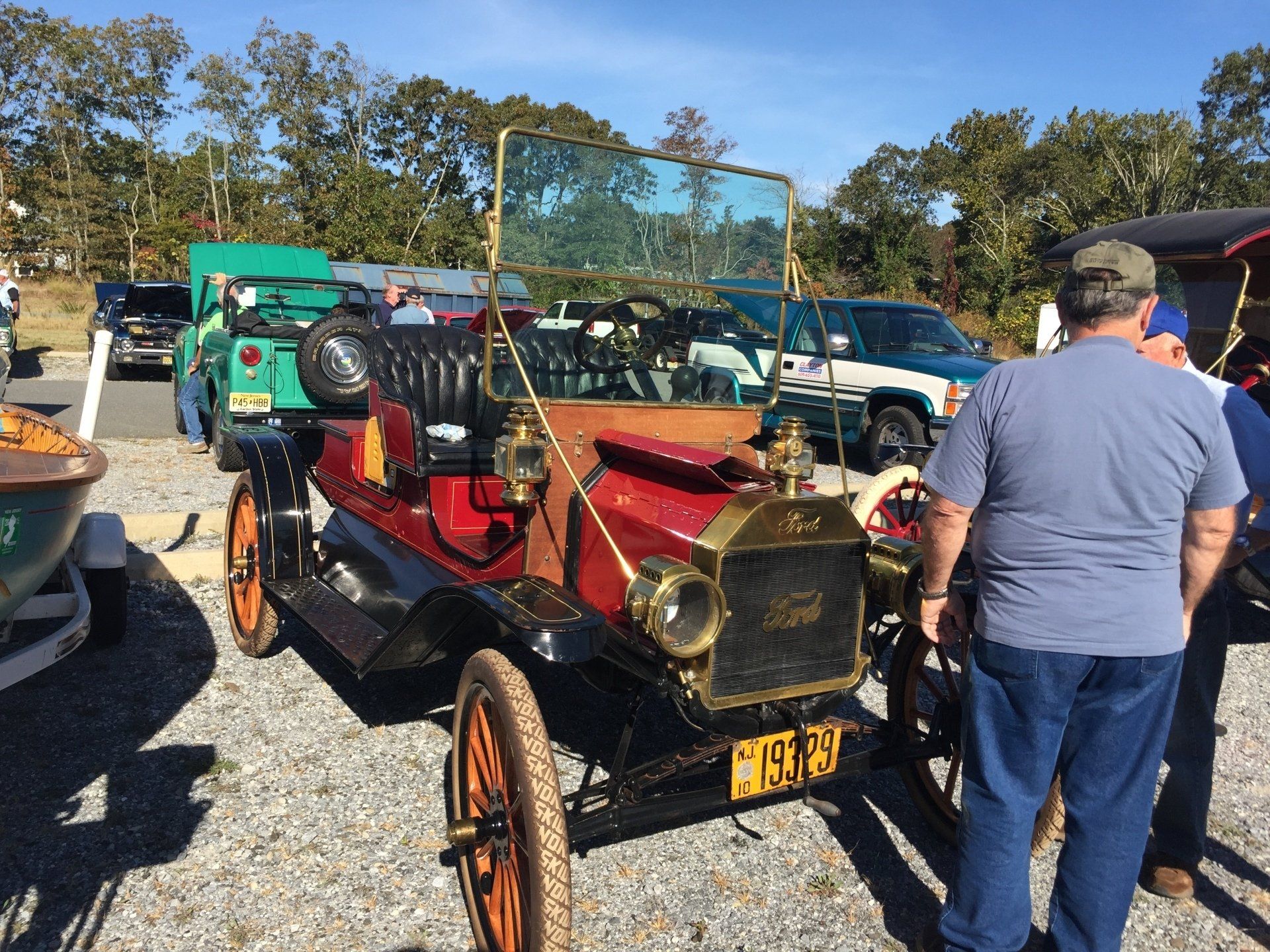 A man is standing next to a red car with a license plate that says 993