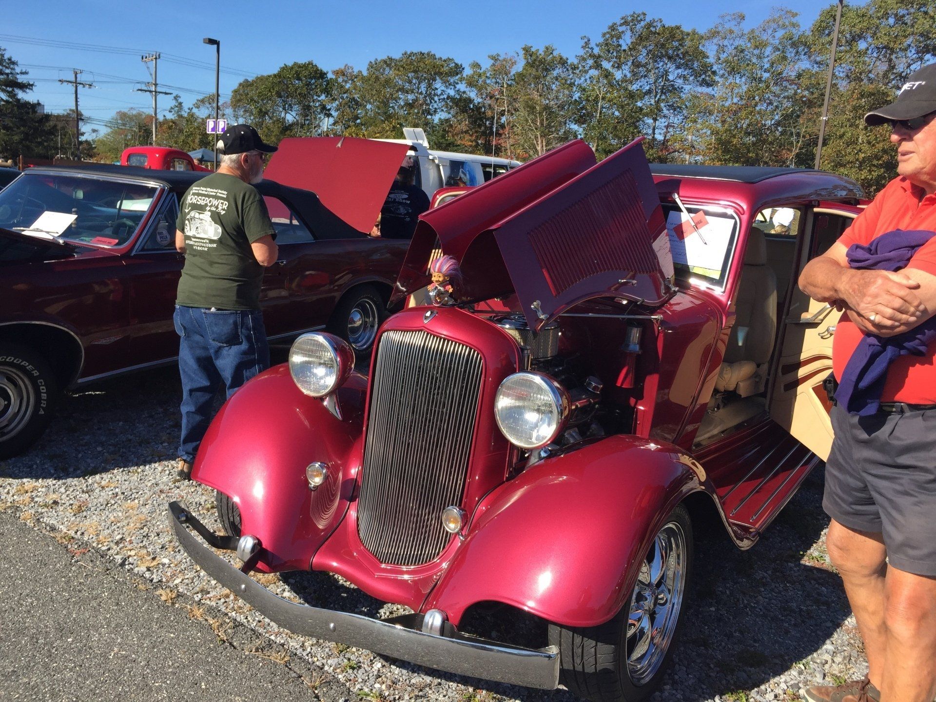 A man is standing next to a red car with the hood open