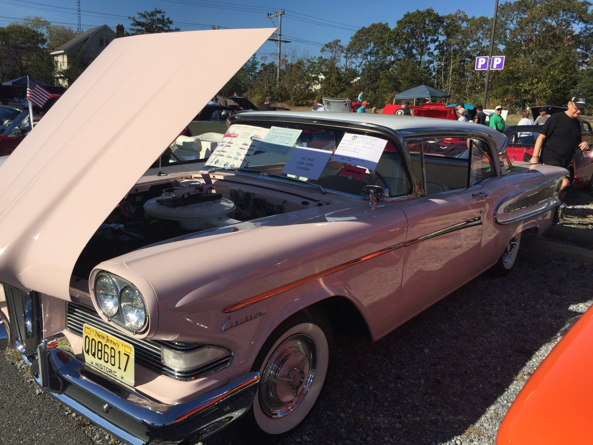 A pink car with the hood up has a new jersey license plate