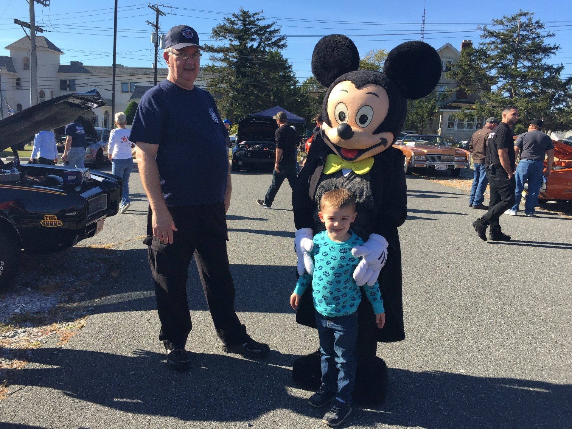 A man stands next to a child and a mickey mouse mascot