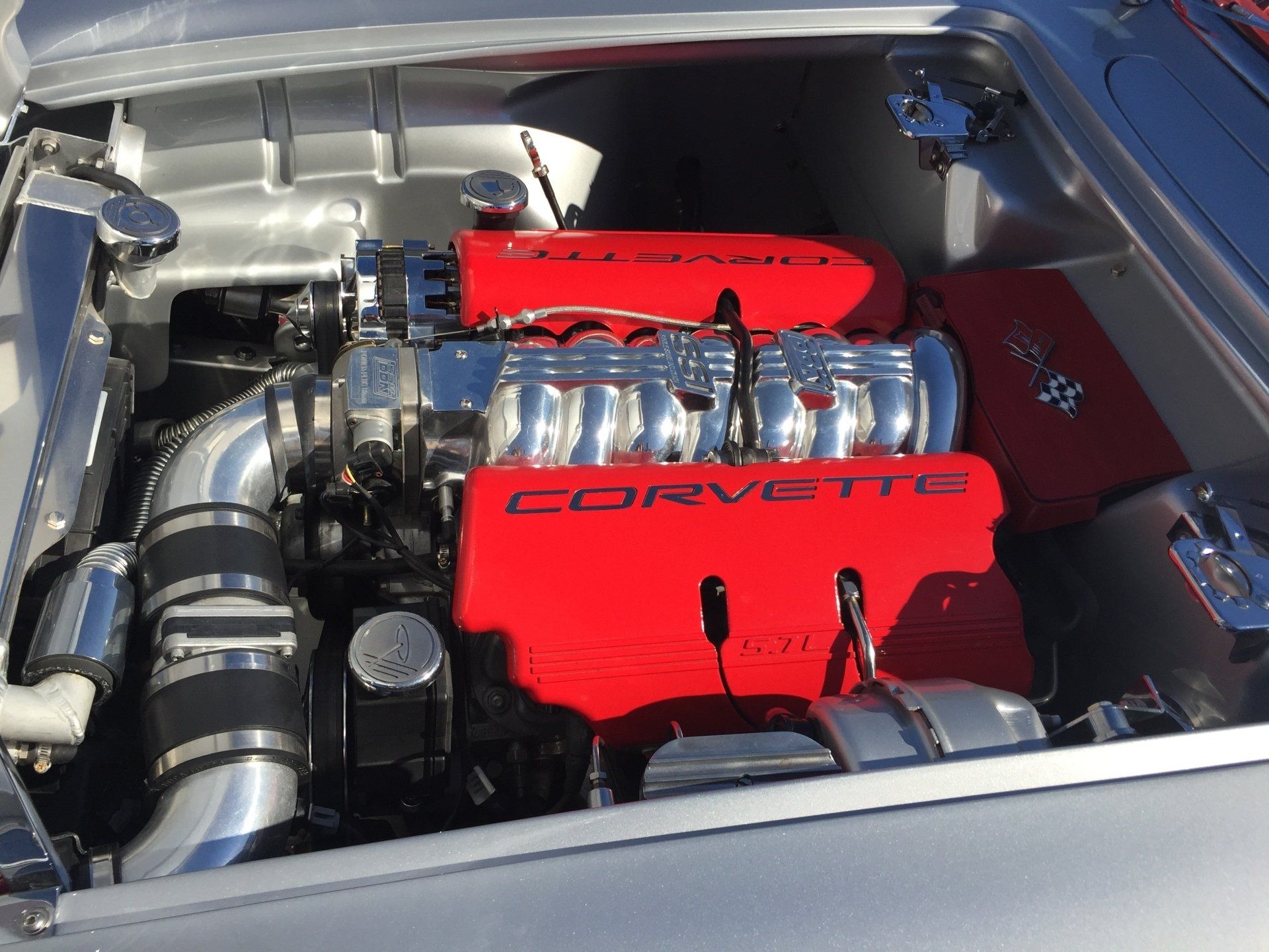 A corvette engine is sitting under the hood of a car