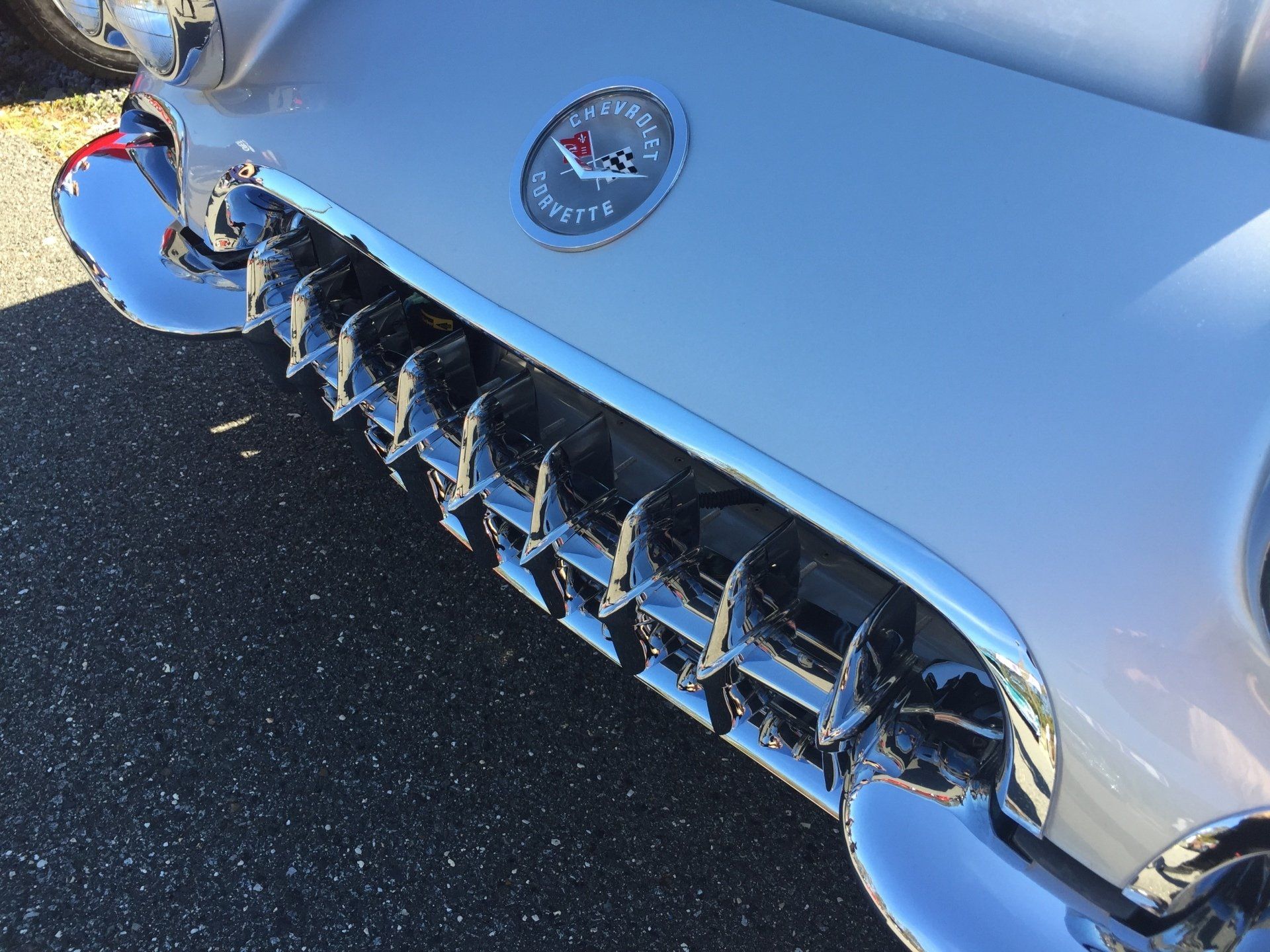 A silver corvette is parked on the side of the road.