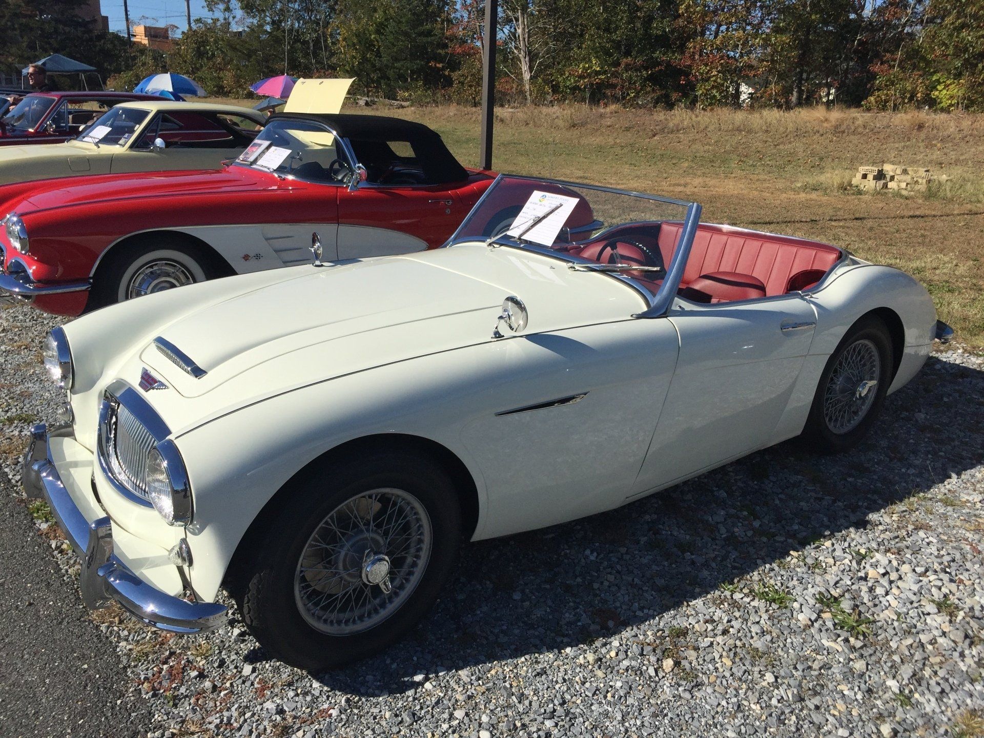 A white sports car is parked next to a red sports car