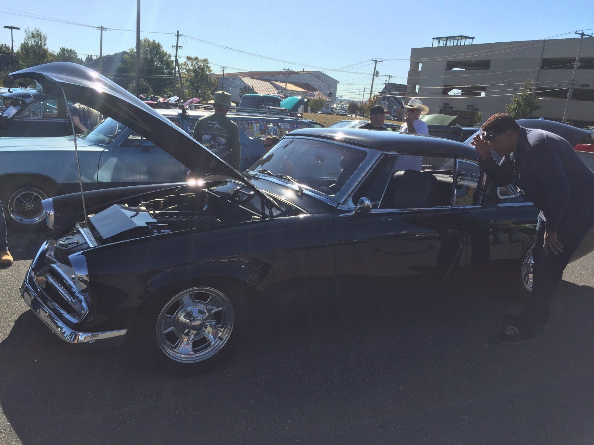 A man standing next to a black car with the hood up