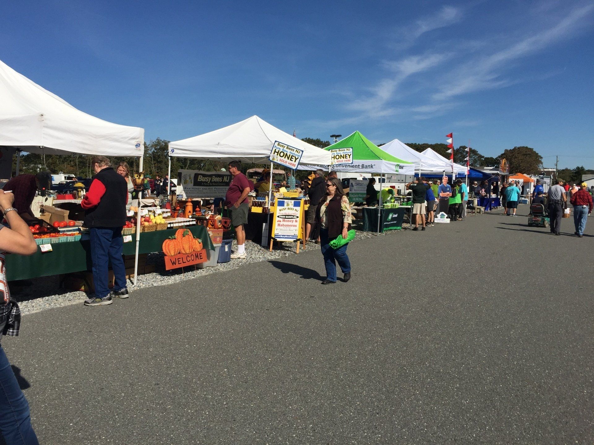 A group of people are standing in a parking lot at a farmer 's market.