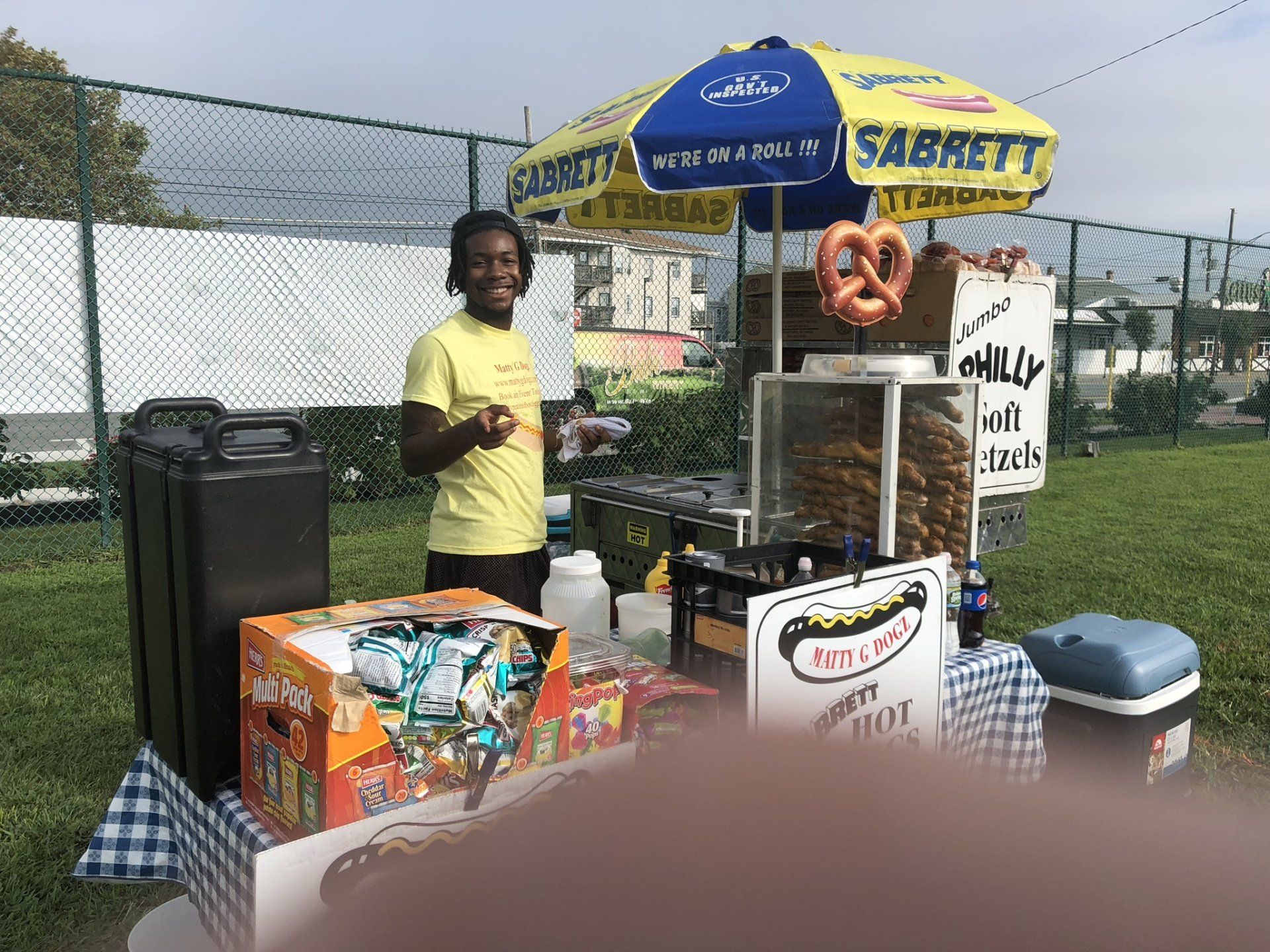 A man is standing in front of a pretzel stand.