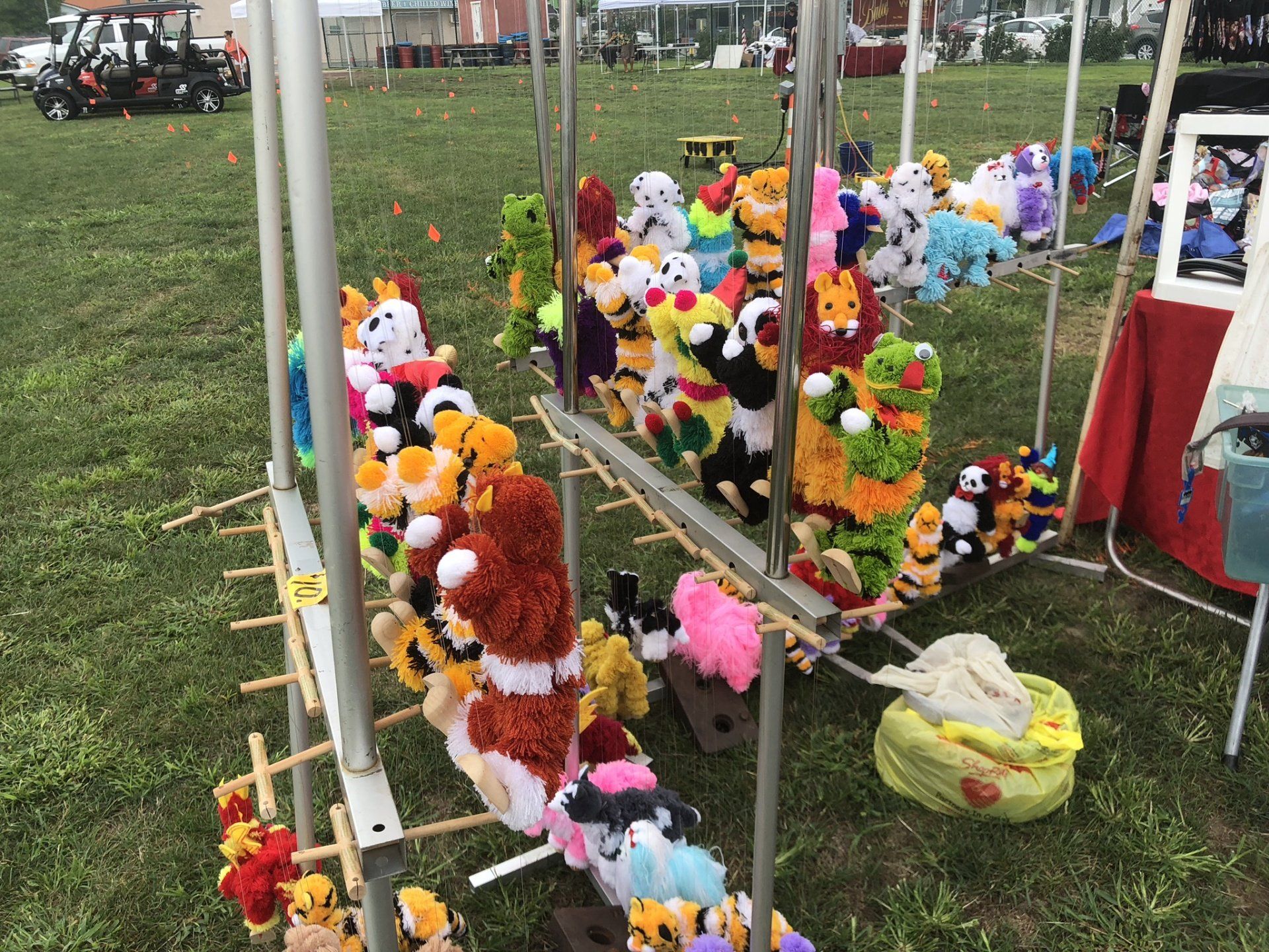 A bunch of stuffed animals are hanging on a rack in a field.