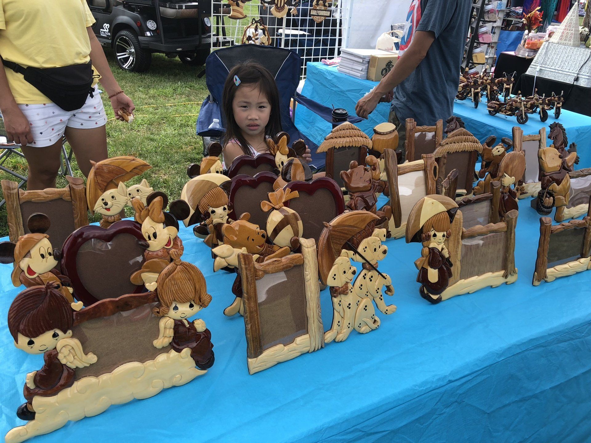 A little girl is sitting at a table with a bunch of stuffed animals on it.