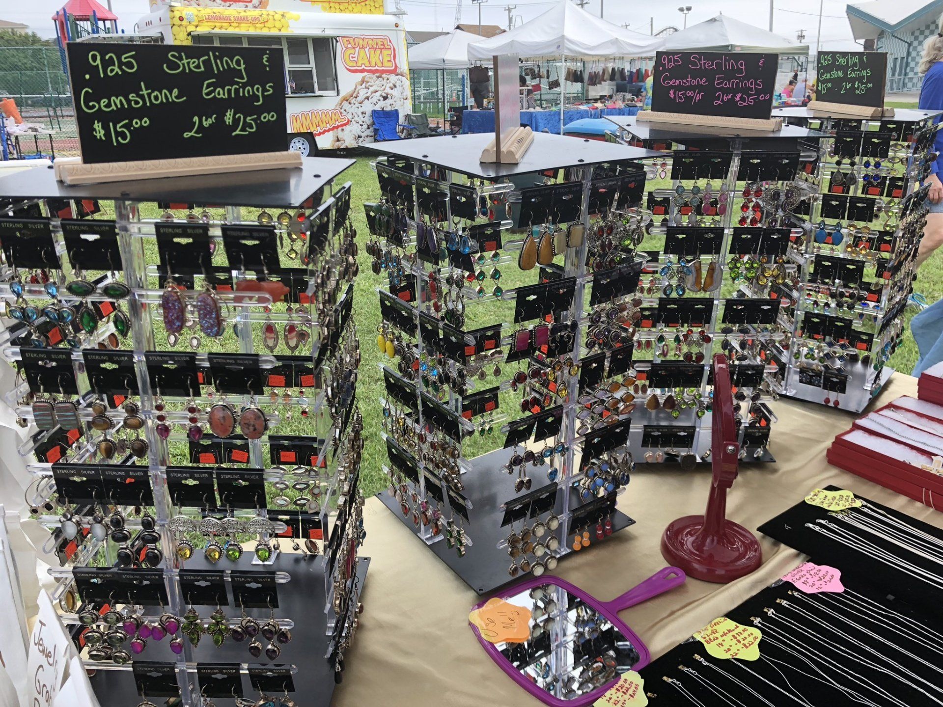 A display of earrings and necklaces with a sign that says 