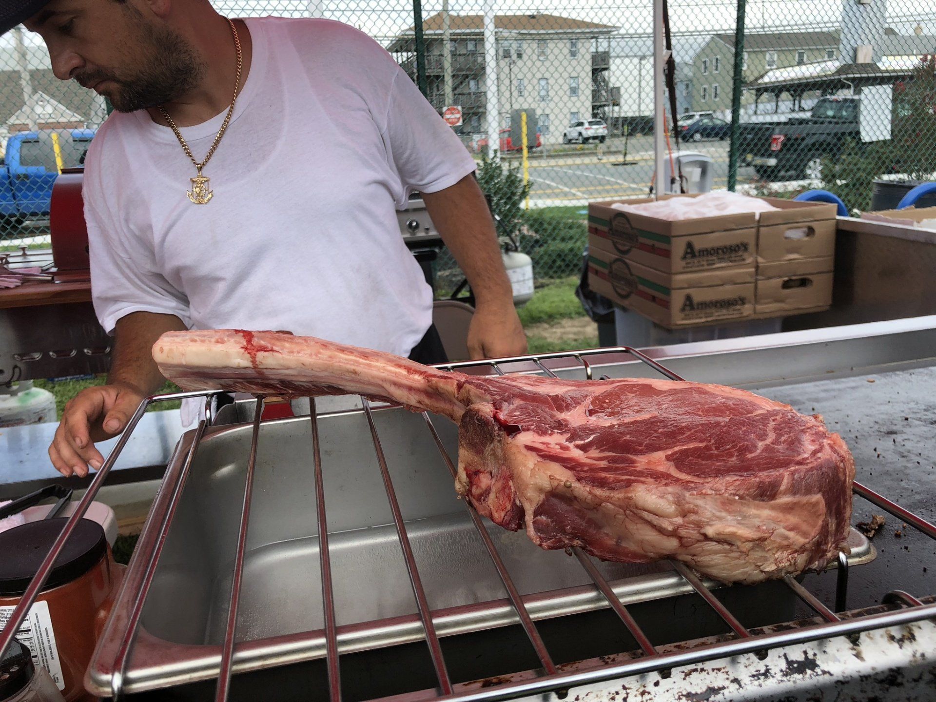 A man is cooking a large piece of meat on a grill.
