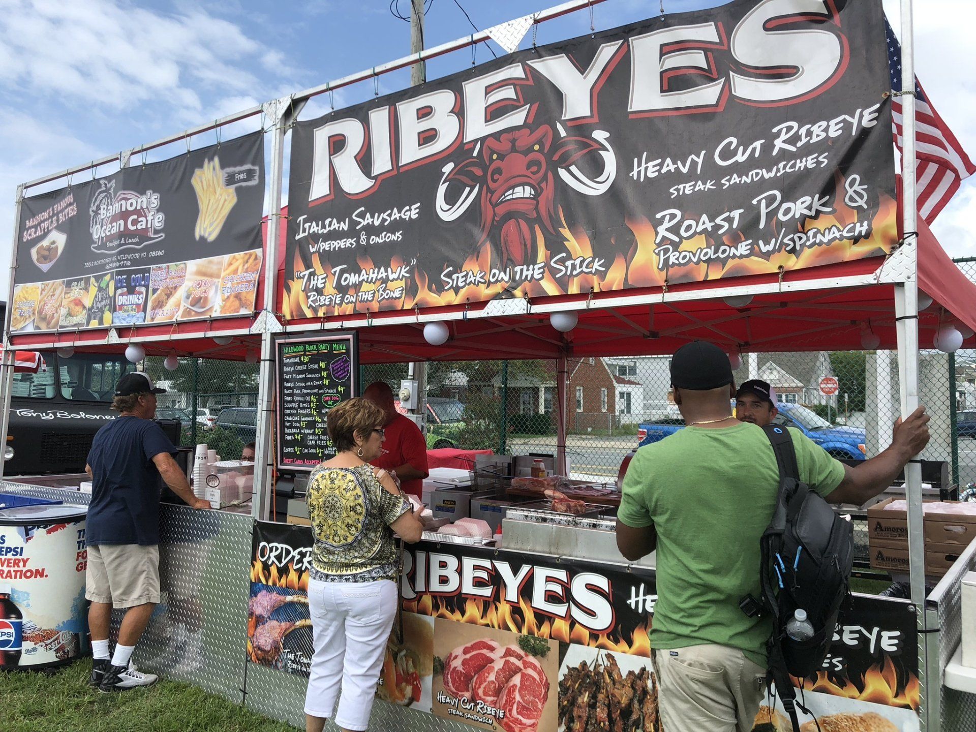 A group of people are standing in front of a food stand.