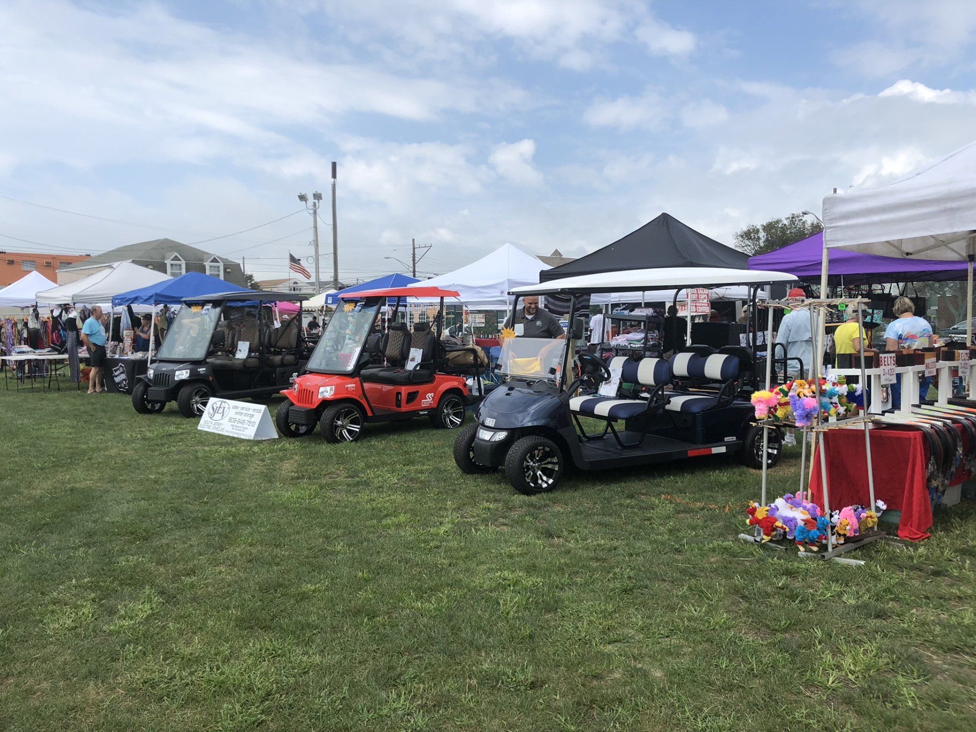 A row of golf carts are parked in a grassy field.