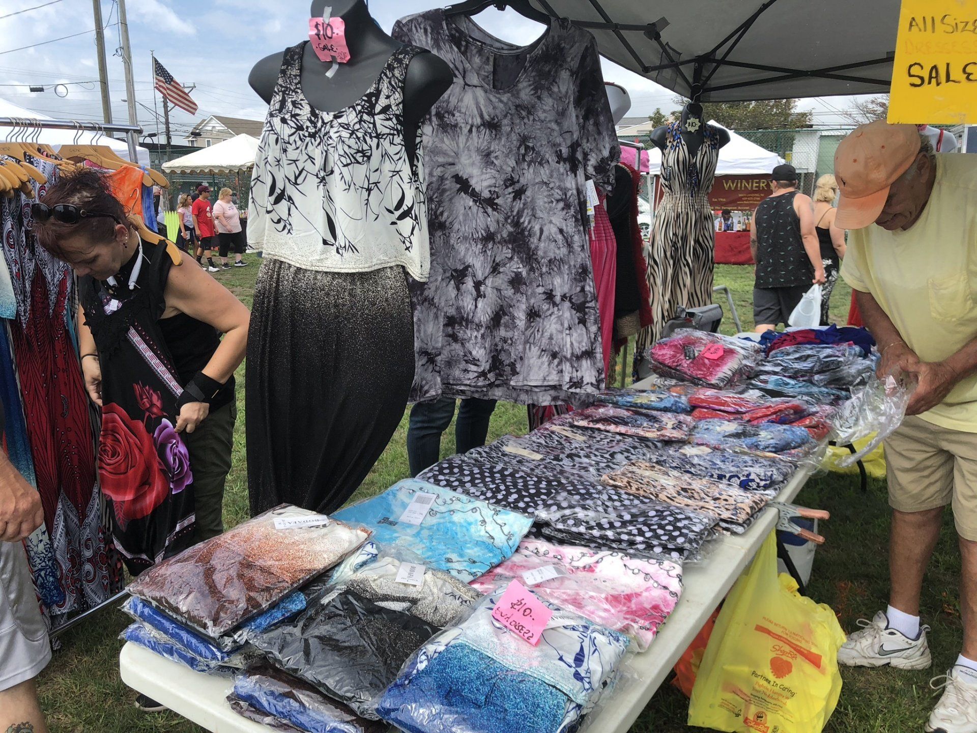 A man is standing in front of a table with clothes on it.