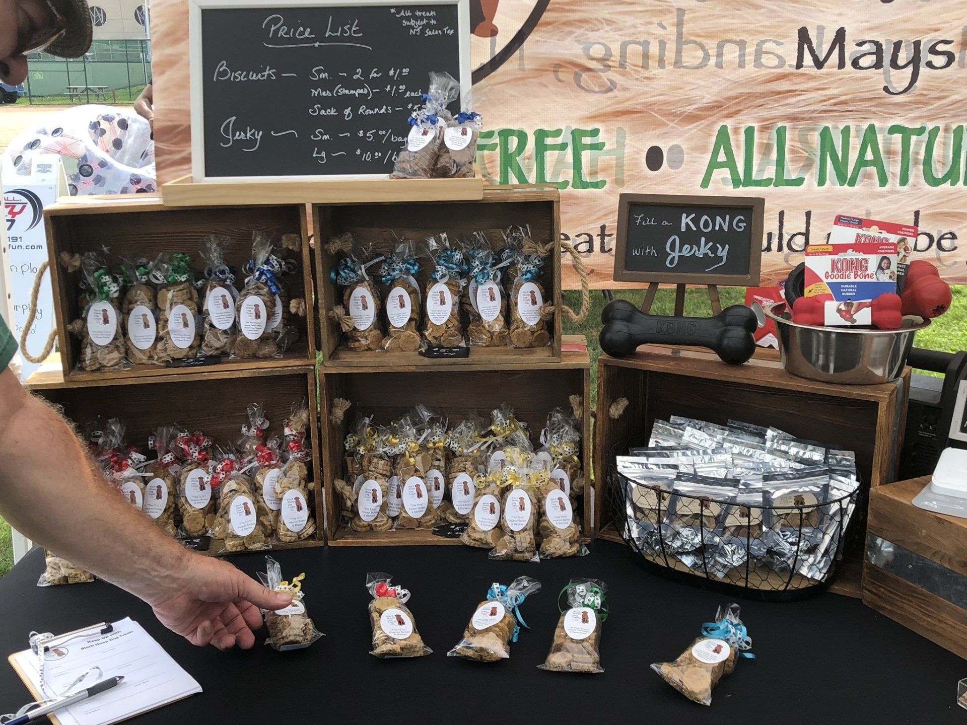 A man is standing in front of a table filled with bags of dog treats.