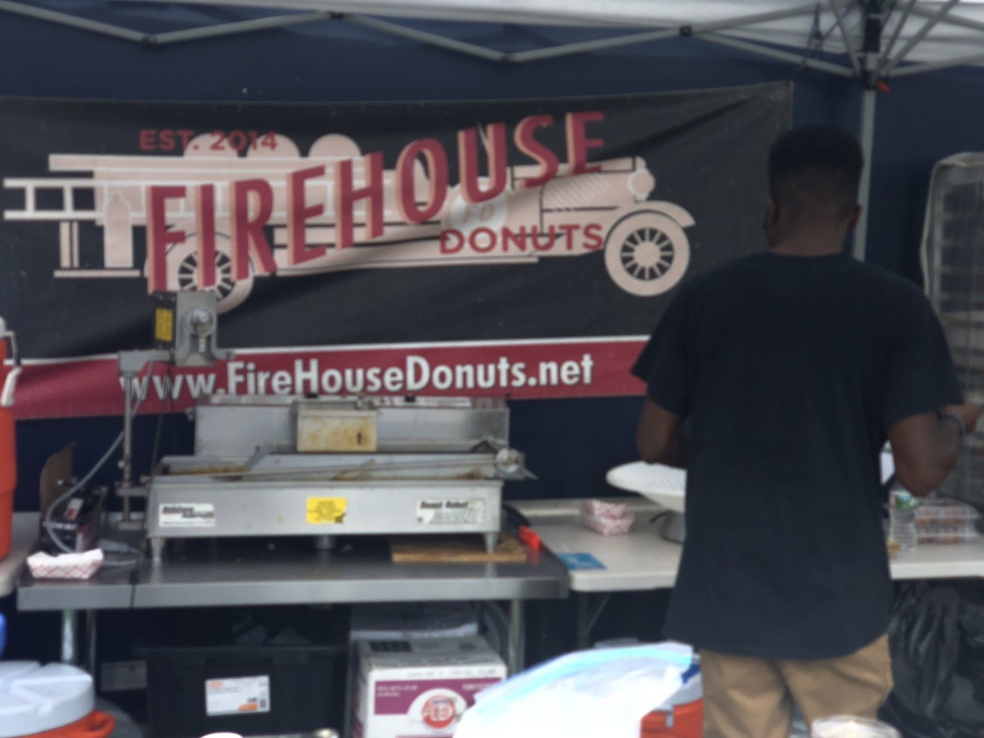 A man stands in front of a sign for firehouse donuts