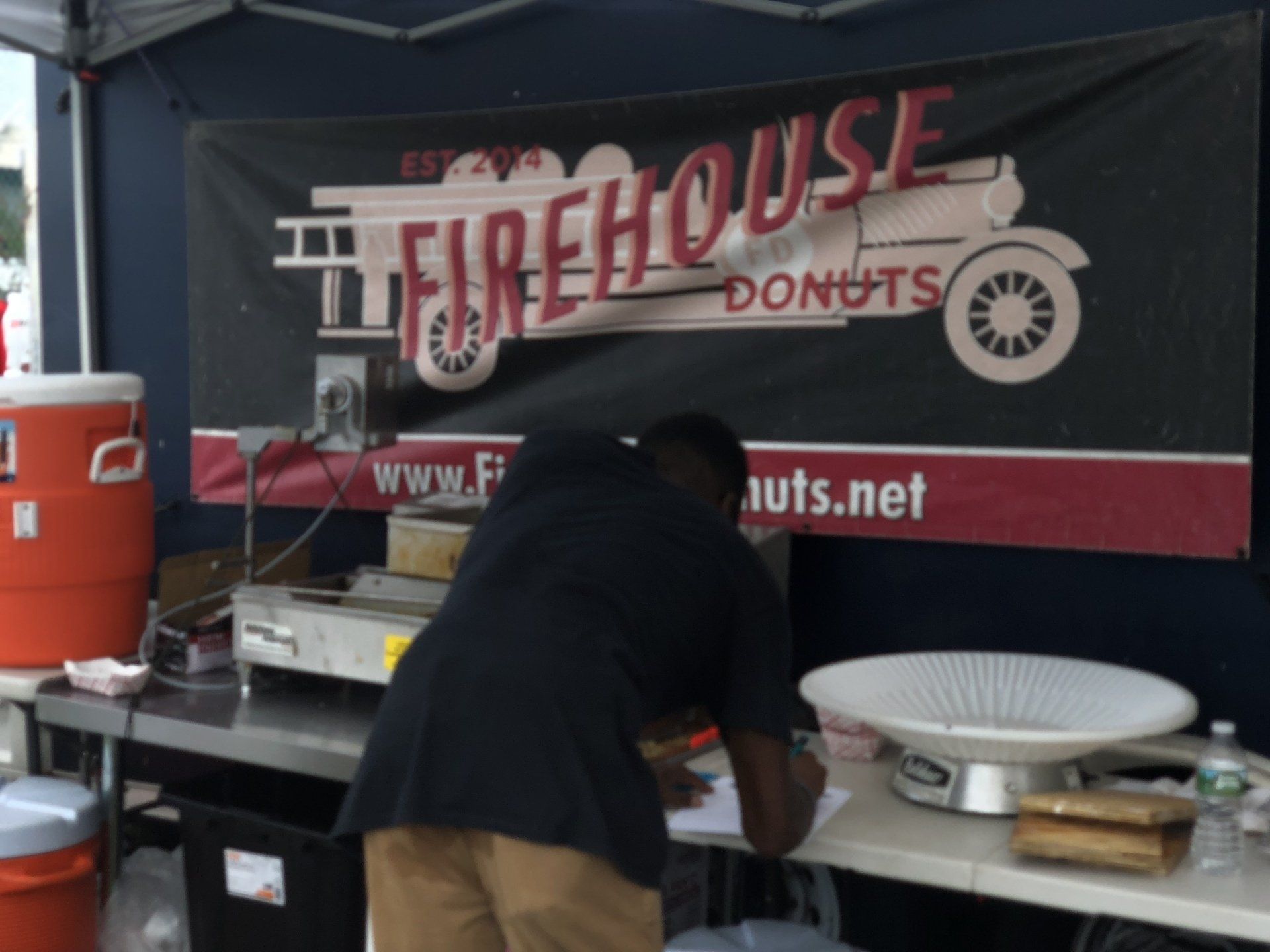 A man standing in front of a sign that says firehouse donuts