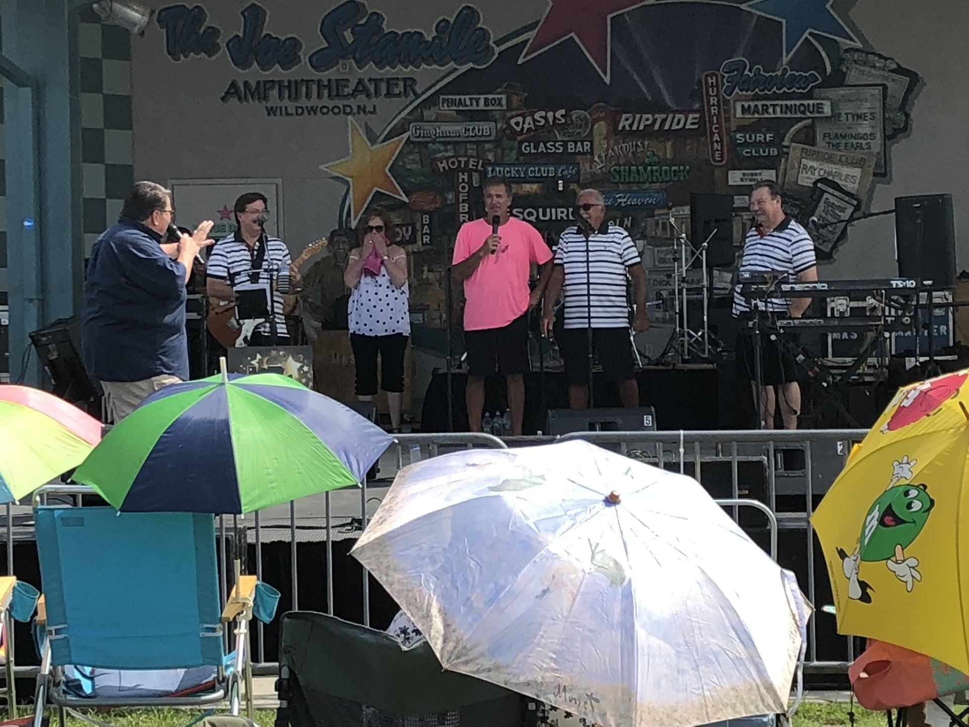 A group of people standing on a stage with umbrellas in front of them.