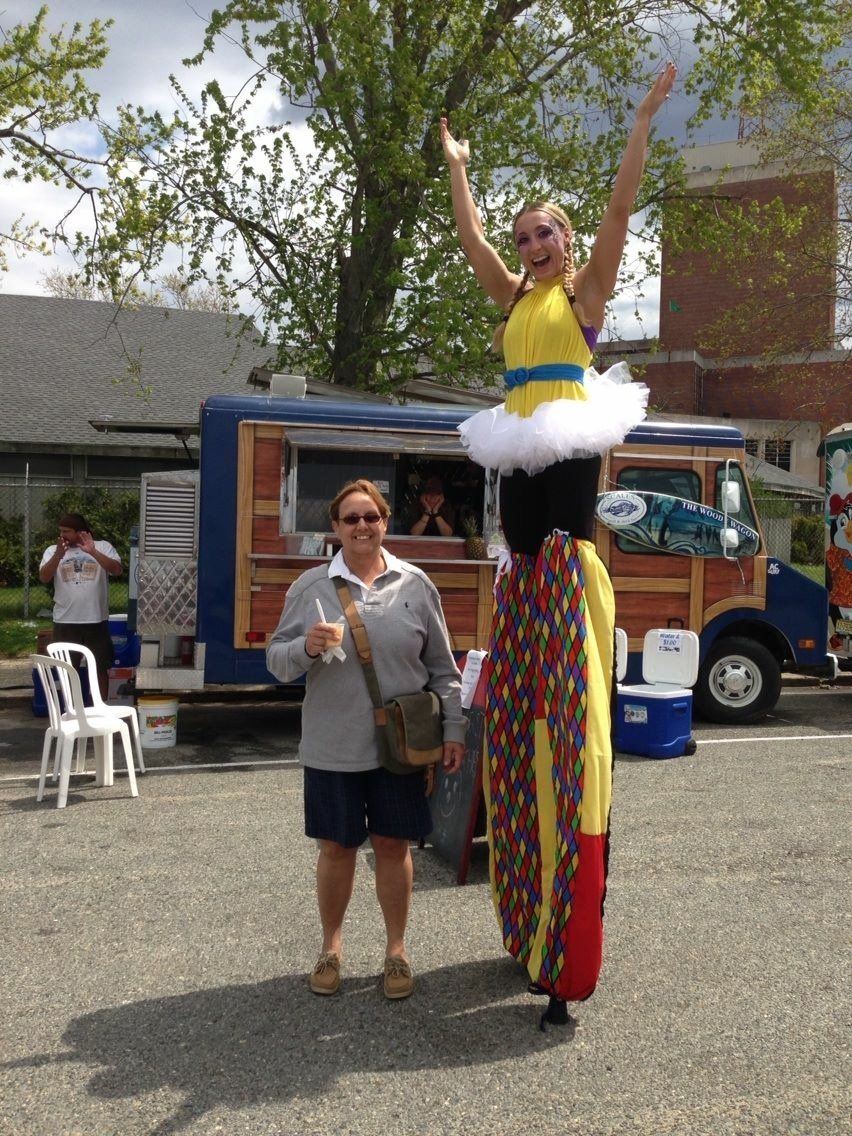 A woman standing next to a woman on stilts