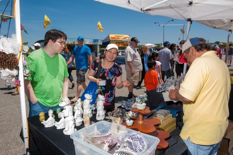A man in a yellow shirt is standing in front of a table full of candles.