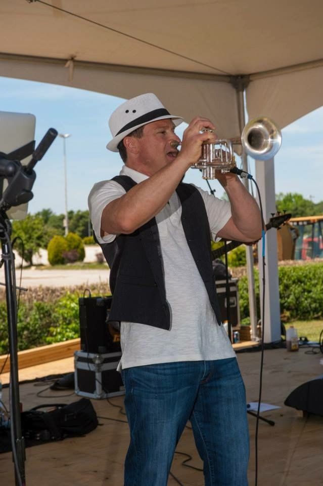 A man in a hat is playing a trumpet in front of a microphone.