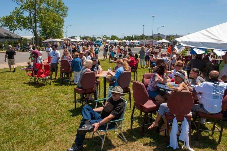 A group of people are sitting at tables and chairs in a park.