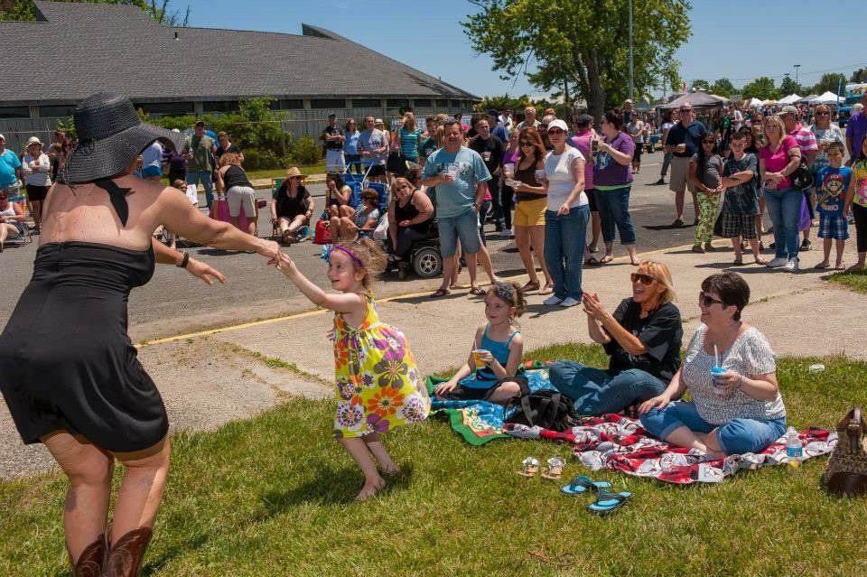 A woman in a black dress is dancing in front of a crowd of people.