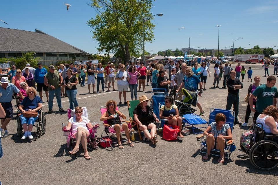 A large group of people are sitting in chairs in a parking lot.