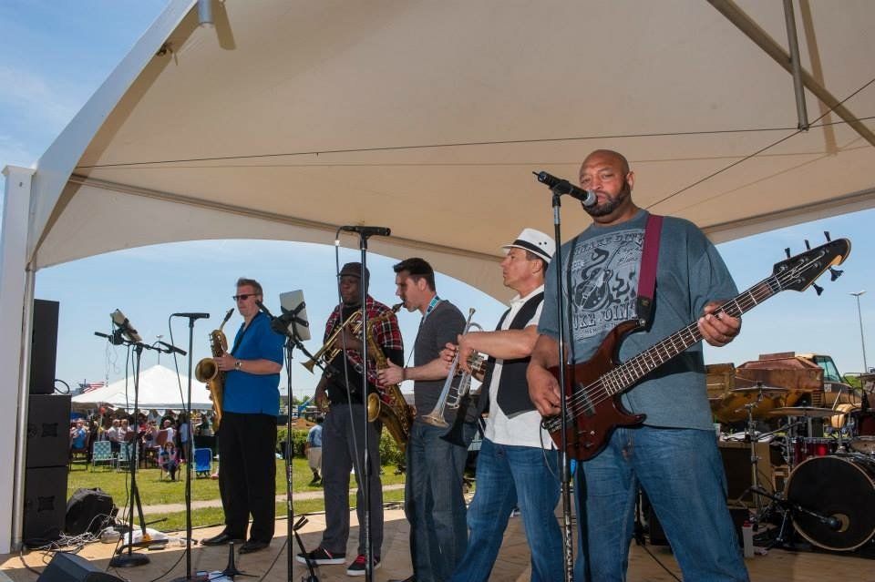 A group of men are playing instruments on a stage under a tent.