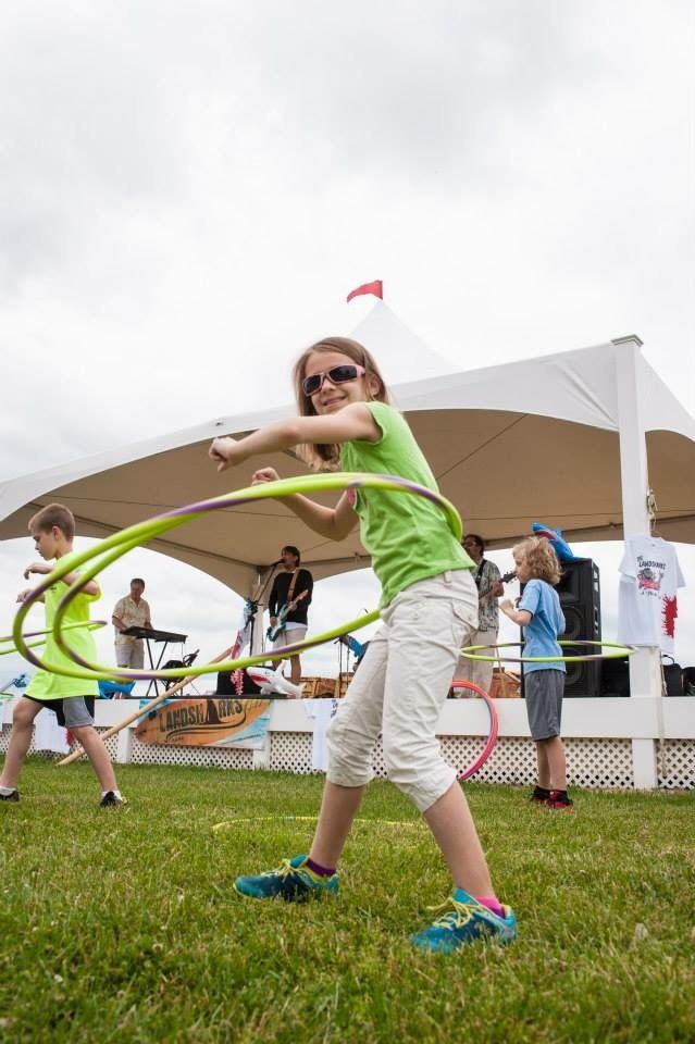 A young girl is playing with a hula hoop in a field.